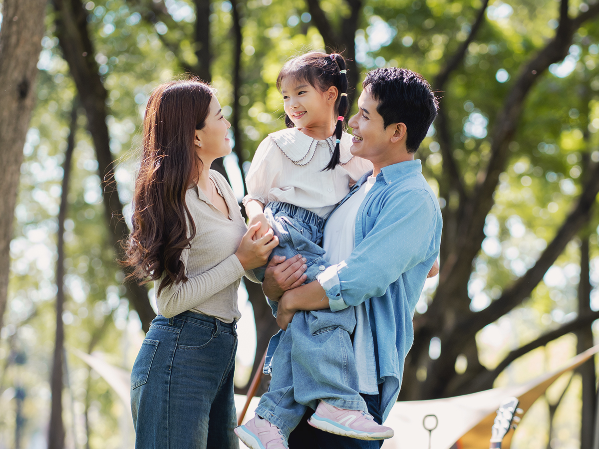 A happy eb5 family walking in their new neighborhood with trees in the background