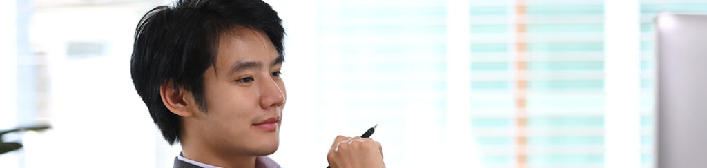 A man pausing with a pen in hand in the middle of reviewing documents as part of doing due diligence eb5